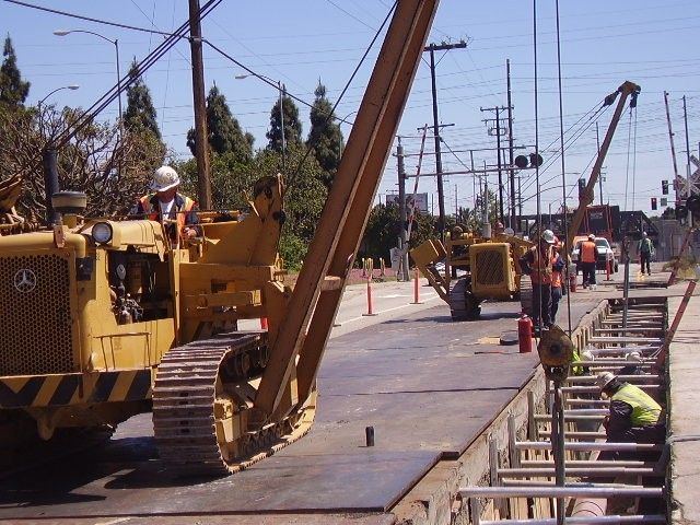 Pipelayer and crew installing pipe on a city street