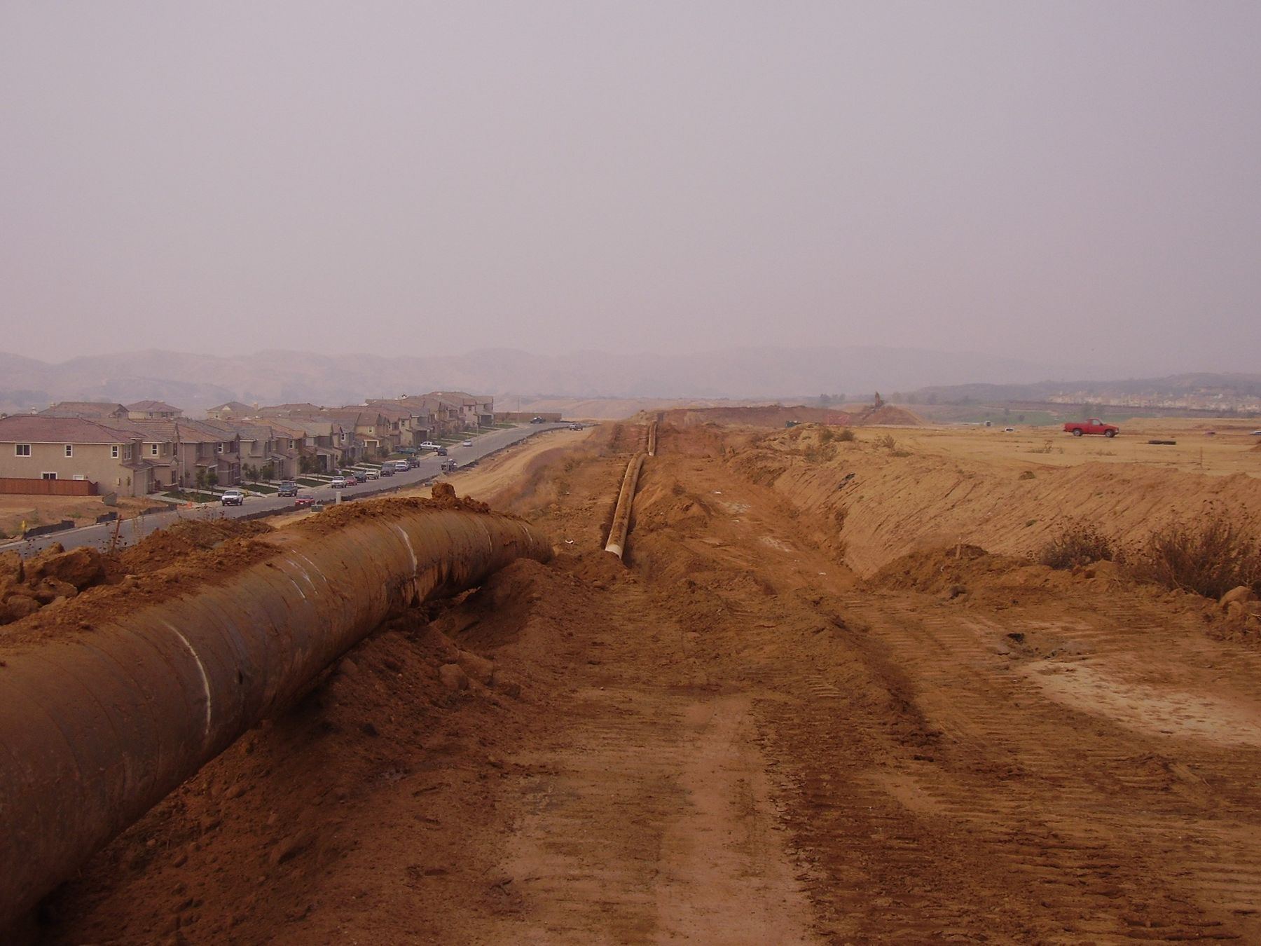 Pipeline laid alongside an open trench on a dirt right-of-way