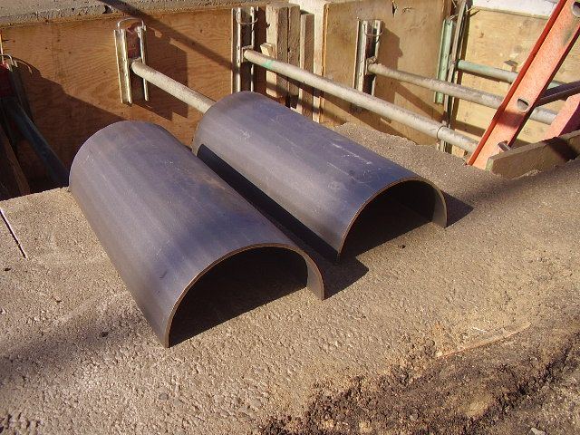 Split steel pipe sleeve sections staged at a job site